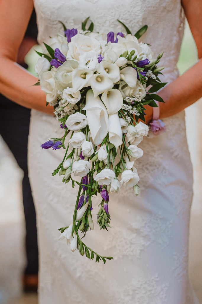 La mariée arrive en tenant son joli bouquet un mélange de fleurs blanches et violettes