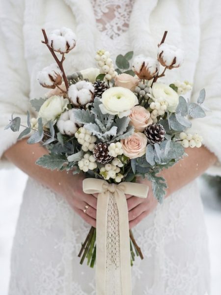 Un joli bouquet de mariée avec des fleurs de coton et des snowberries pour un mariage d'hiver
